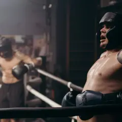 Two boxers in a ring, one leaning on the ropes, sweat glistening. This intense roadwork boxing session shows the grit and determination of the fighters.