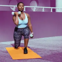 Woman performing lunges with dumbbells, building shoulder endurance exercises.