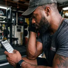 Man with red beard wearing a neck harness in a home gym.
