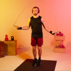 A boxer with headphones jumps rope, a common training method to improve stamina and agility. How long do boxers jump rope? It varies, but often for 10-15 minutes per round.