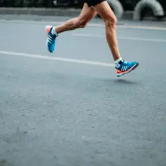 A runner's legs in motion, wearing blue and orange sneakers. This image evokes the dedication required to train, making one wonder how many miles do boxers run to achieve peak fitness.