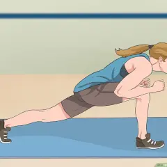 Woman performing a dynamic jumping lunges exercise on a blue mat, demonstrating proper form for an explosive workout.