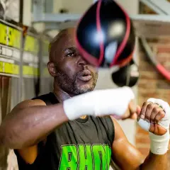 A young Bernard Hopkins, sweat glistening, trains intensely with a speed bag in a boxing gym.