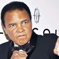 Muhammad Ali, the greatest of all time, in a boxing stance. He wears a tuxedo with a bow tie.
