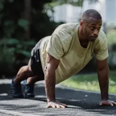 A determined boxer performs push-ups outdoors. This exercise builds the upper body strength crucial for delivering powerful punches and absorbing blows.