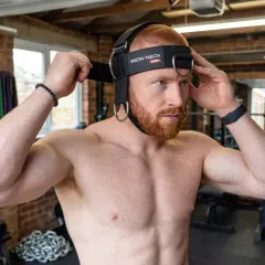 Man adjusting a neck weight harness, ready to train his neck muscles. Discover the neck weight harness benefits for strength and posture.