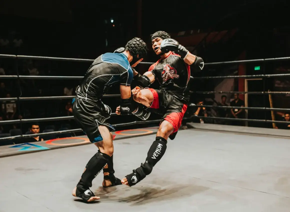 Two fighters in a ring, one delivering a powerful kick. The intensity of the moment showcases the mental fortitude and boxing psychology required for combat sports.