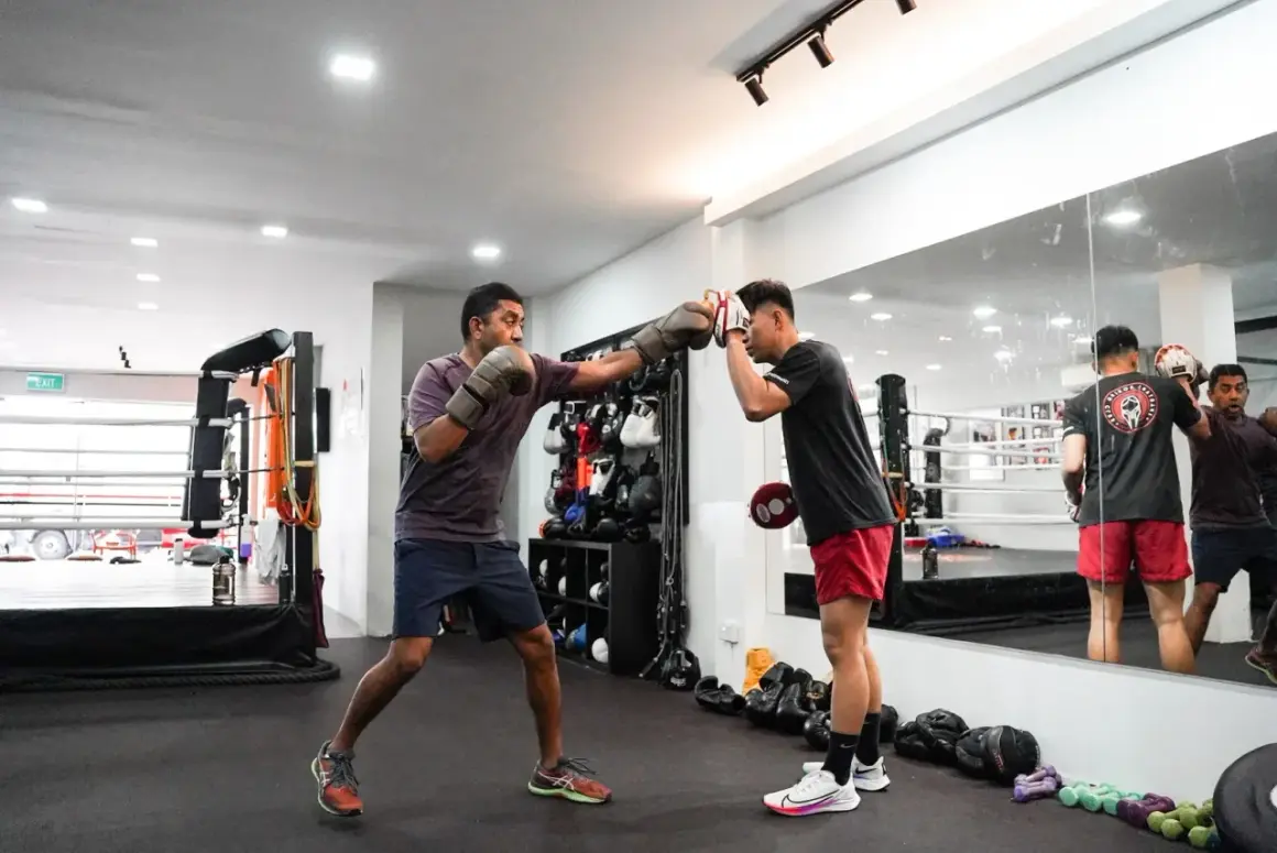 Two men train in a boxing gym, one throwing a punch while the other defends. This image captures the intense **boxing mindset** required for the sport.