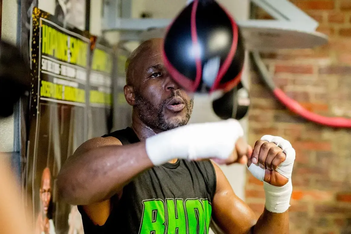 A young Bernard Hopkins, sweat glistening, trains intensely with a speed bag in a boxing gym.