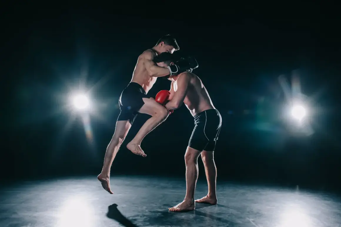 Two boxers spar intensely. One leaps, delivering a knee strike while the other defends. This dynamic action shows how boxers do calisthenics for explosive power.