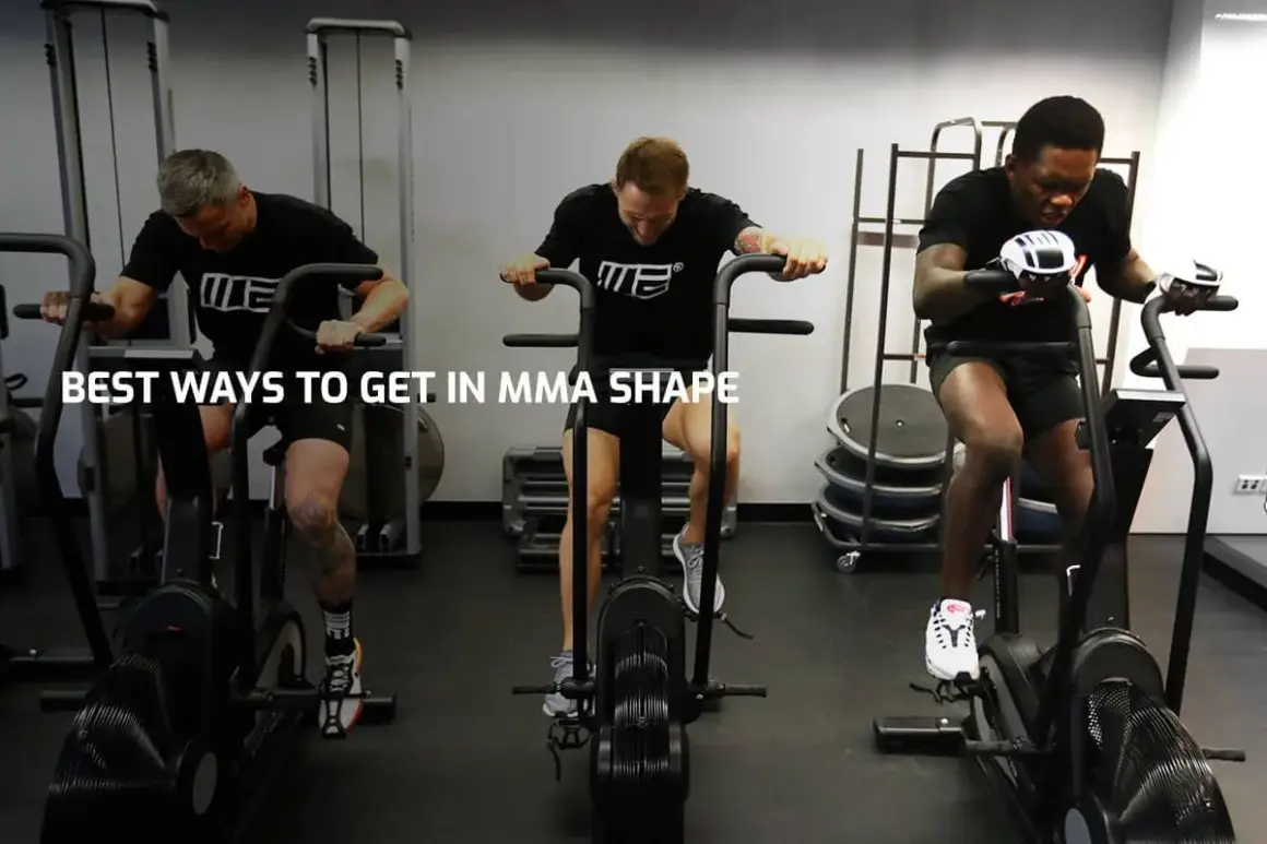 Three men with impressive fighters physique train on air bikes in a gym, showcasing their dedication to peak physical condition.