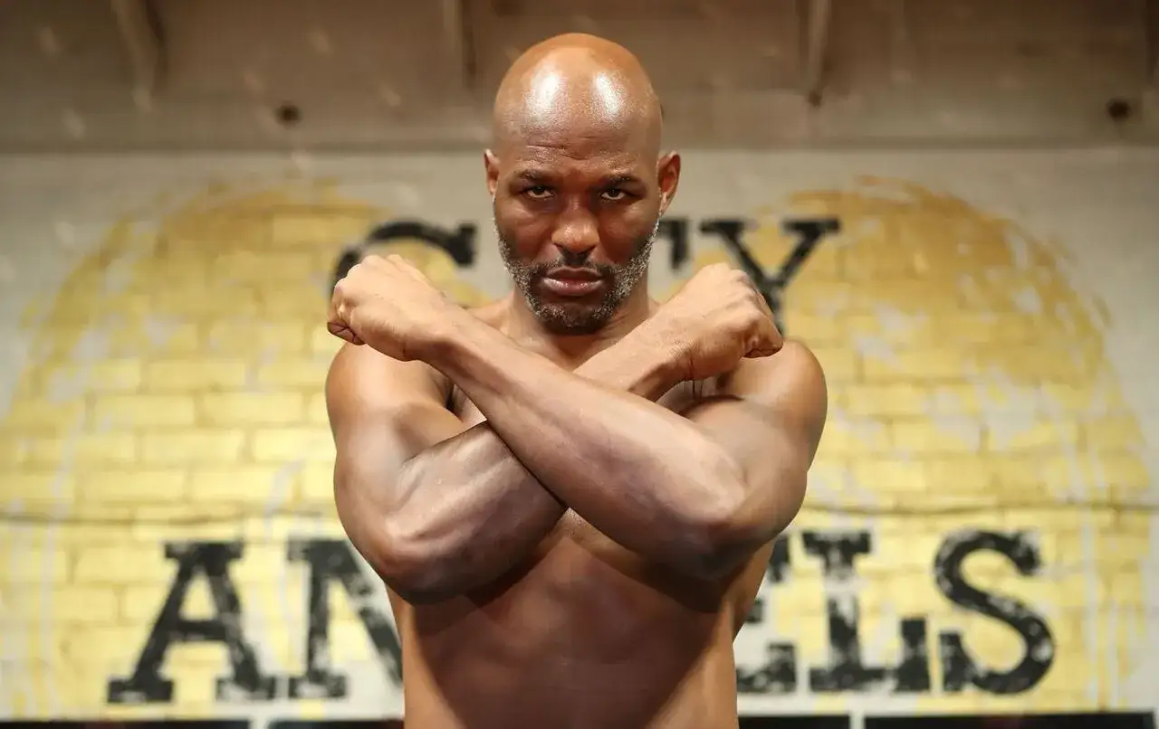 A determined Bernard Hopkins, looking young and ready, poses with crossed arms in a boxing ring.