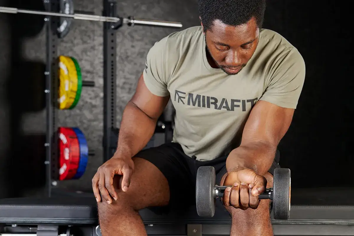 Man performing dumbbell wrist curls, a great exercise for how to get stronger wrists.