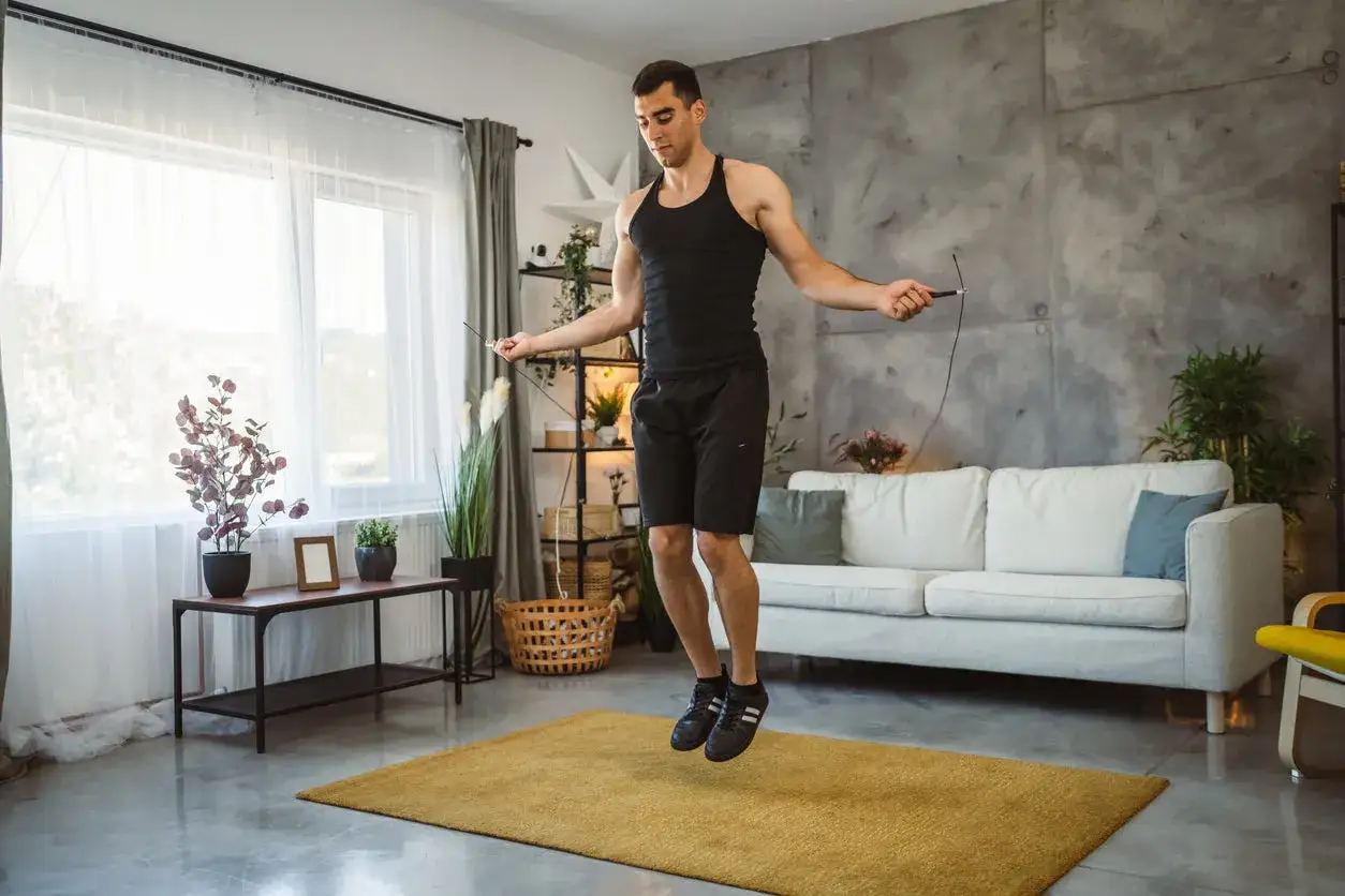 Man jumps rope indoors, a great cardio alternative to burpees.