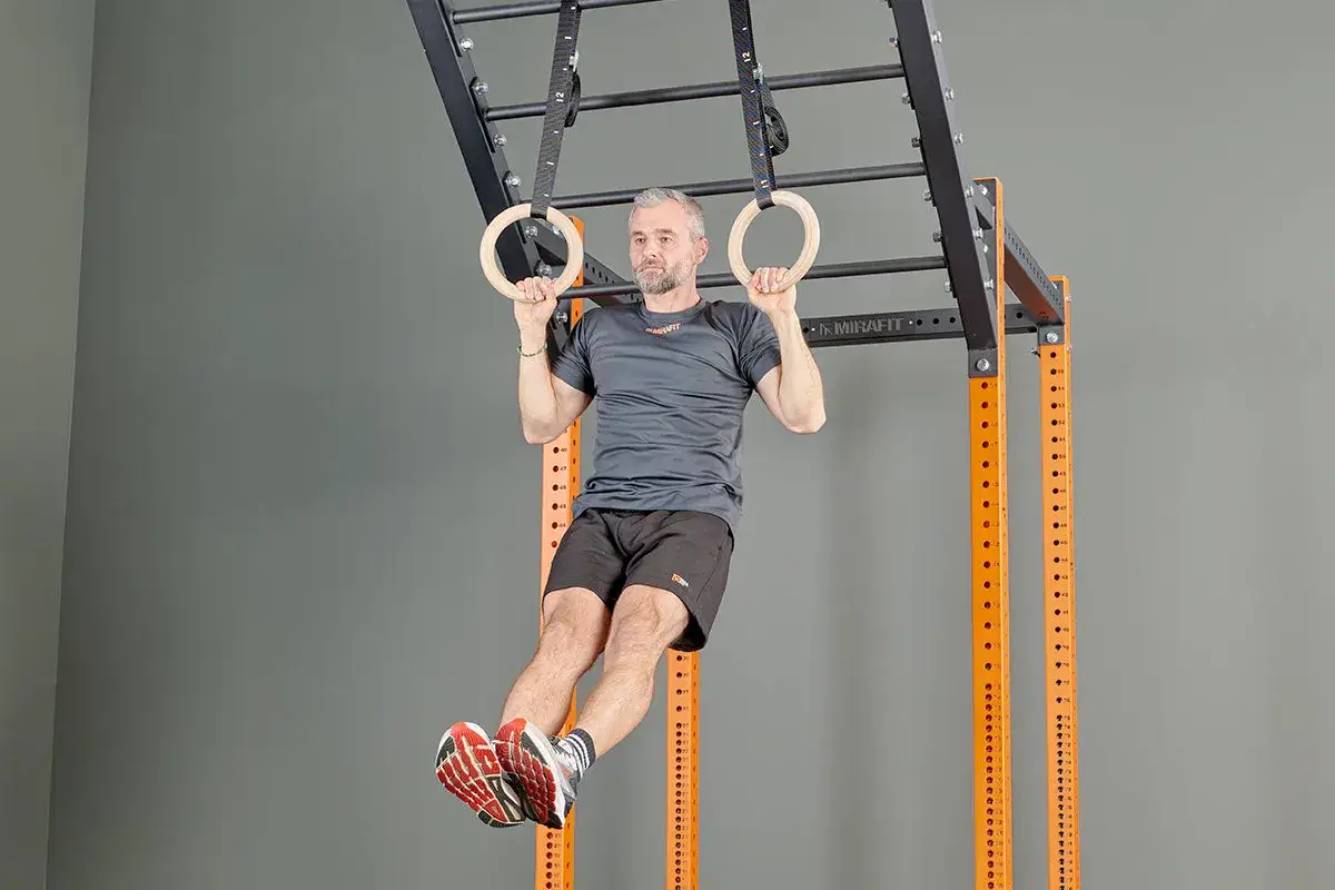 A man performs a hanging leg raise on gymnastic rings, demonstrating how boxers do calisthenics for core strength and agility.